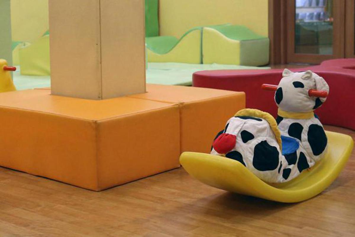 Ingresso scuola materna con cancello, bambini piccoli in aula, aree esterne con giochi per infanzia, immagine di approfondimento