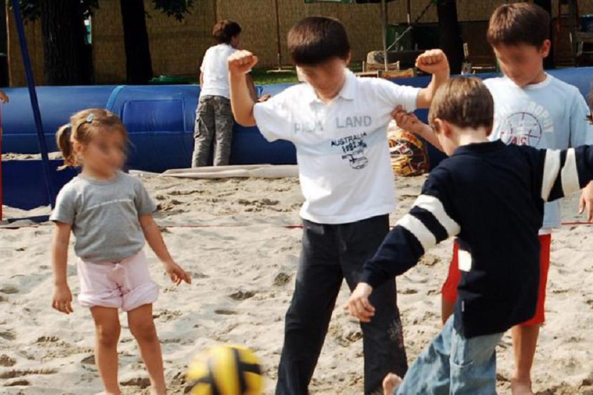 Bambini che giocano all'aperto durante l'estate, con supervisione di adulti vicini