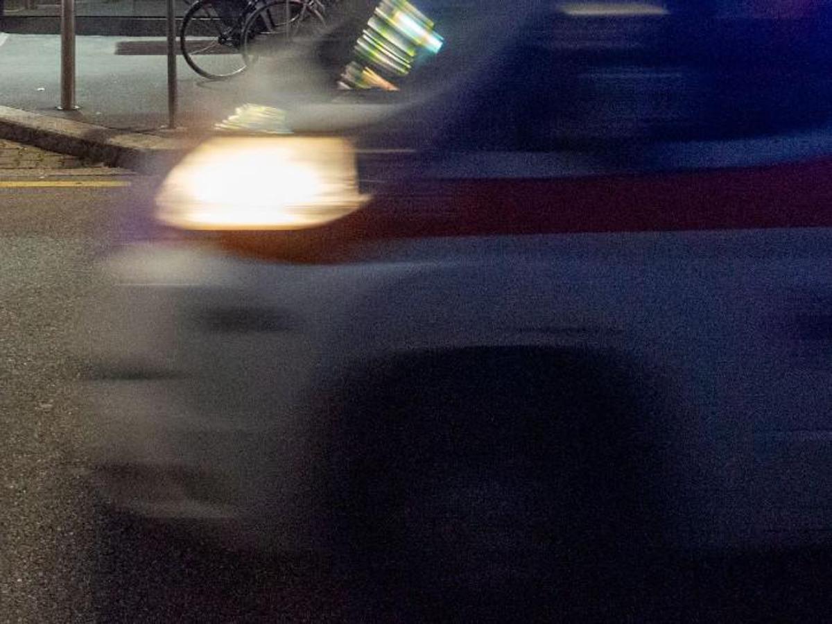 Strada notturna con monopattino abbandonato, auto ferma e soccorsi in corso