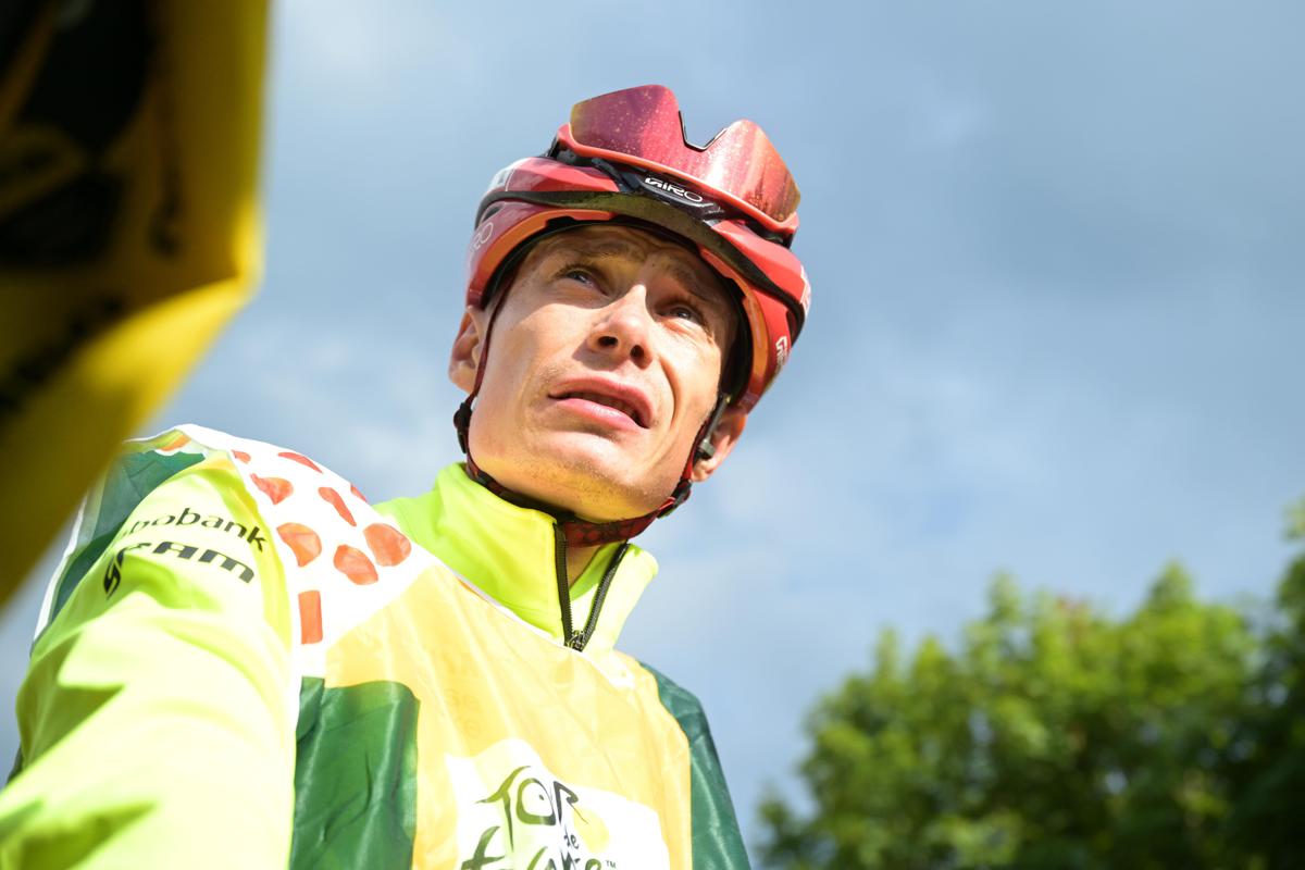 Corridore in maglia da gara ritirato da una strada di montagna dopo incidente in curva, immagine di approfondimento