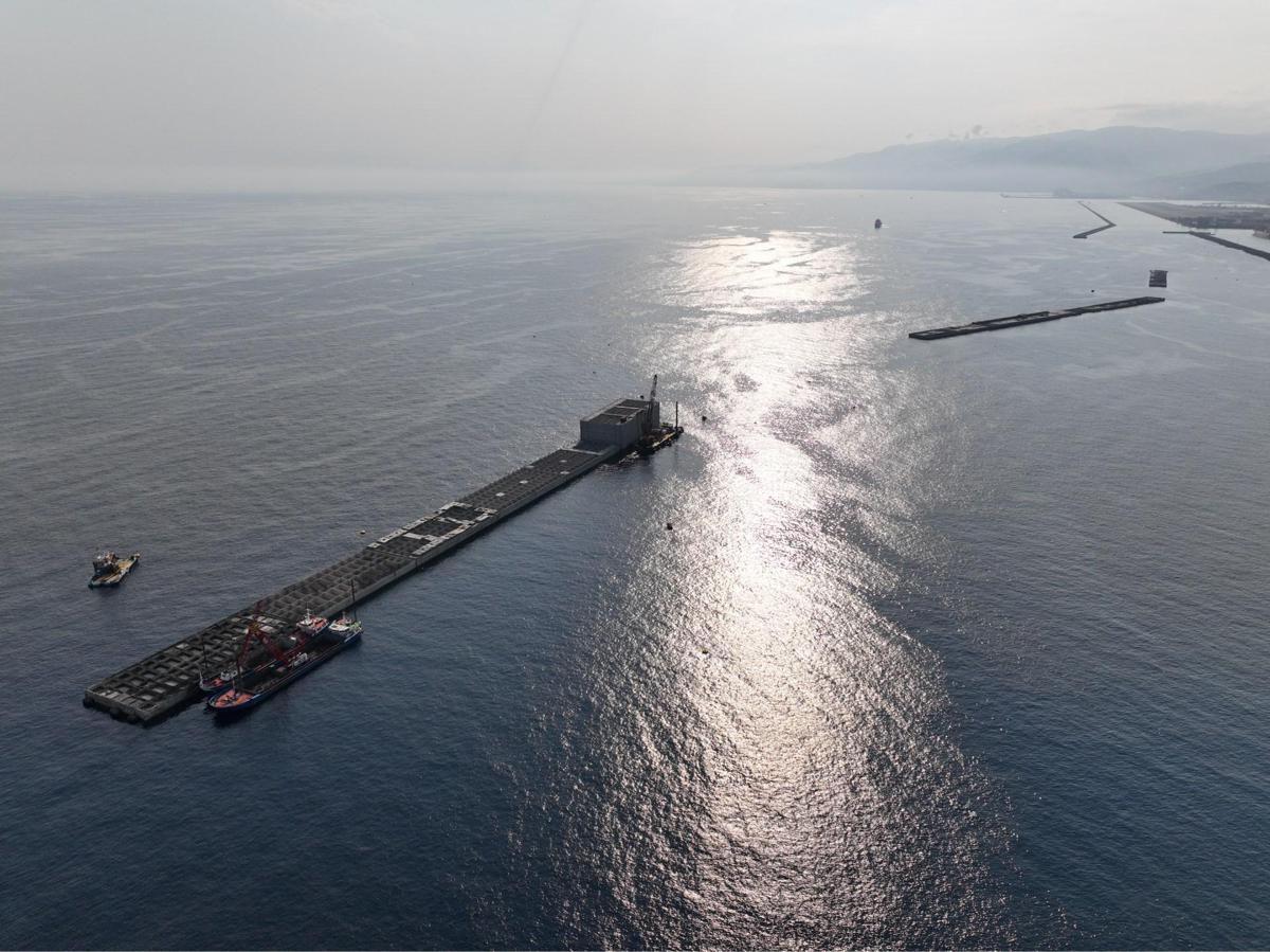 Cantiere in mare della diga foranea di Genova, con cassone in posa, gru e attrezzature portuali sullo sfondo
