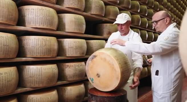 Forme di formaggio Parmigiano Reggiano in caseificio di montagna, paesaggio appenninico sullo sfondo, immagine di approfondimento