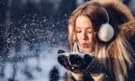 Donna con cuffie e guanti guarda la neve che cade