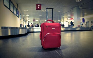 Valigia rossa su nastro trasportatore in aeroporto