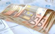 Mazzetta di banconote in euro posate su una bolletta.