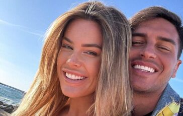 Primo piano di Sophie Codegoni con capelli biondi e Alessandro Basciano che sorridono felici all'aperto, con il mare sullo sfondo