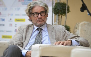 Paolo Del Debbio, giornalista e conduttore televisivo, seduto con un microfono davanti